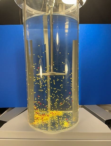 A glass cylinder with yellow and white specks inside of it.