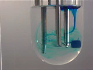 A blue liquid is being poured into a glass.