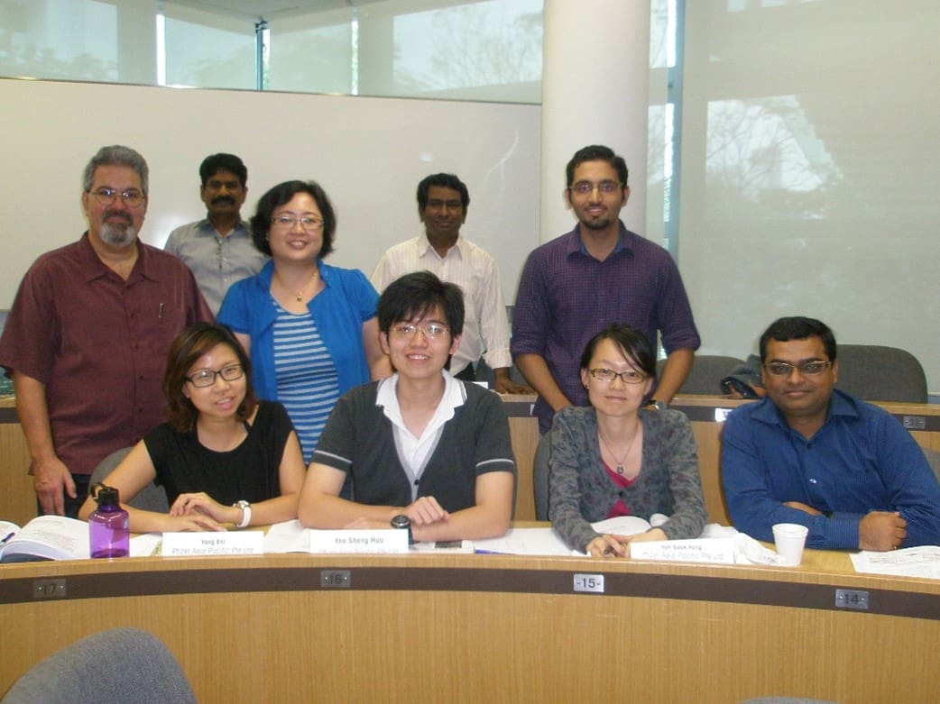 A group of people sitting at a table in front of a wall.