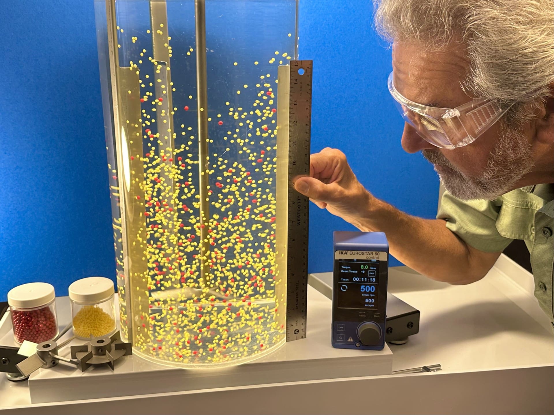 A man looking at the bottom of a glass cylinder.